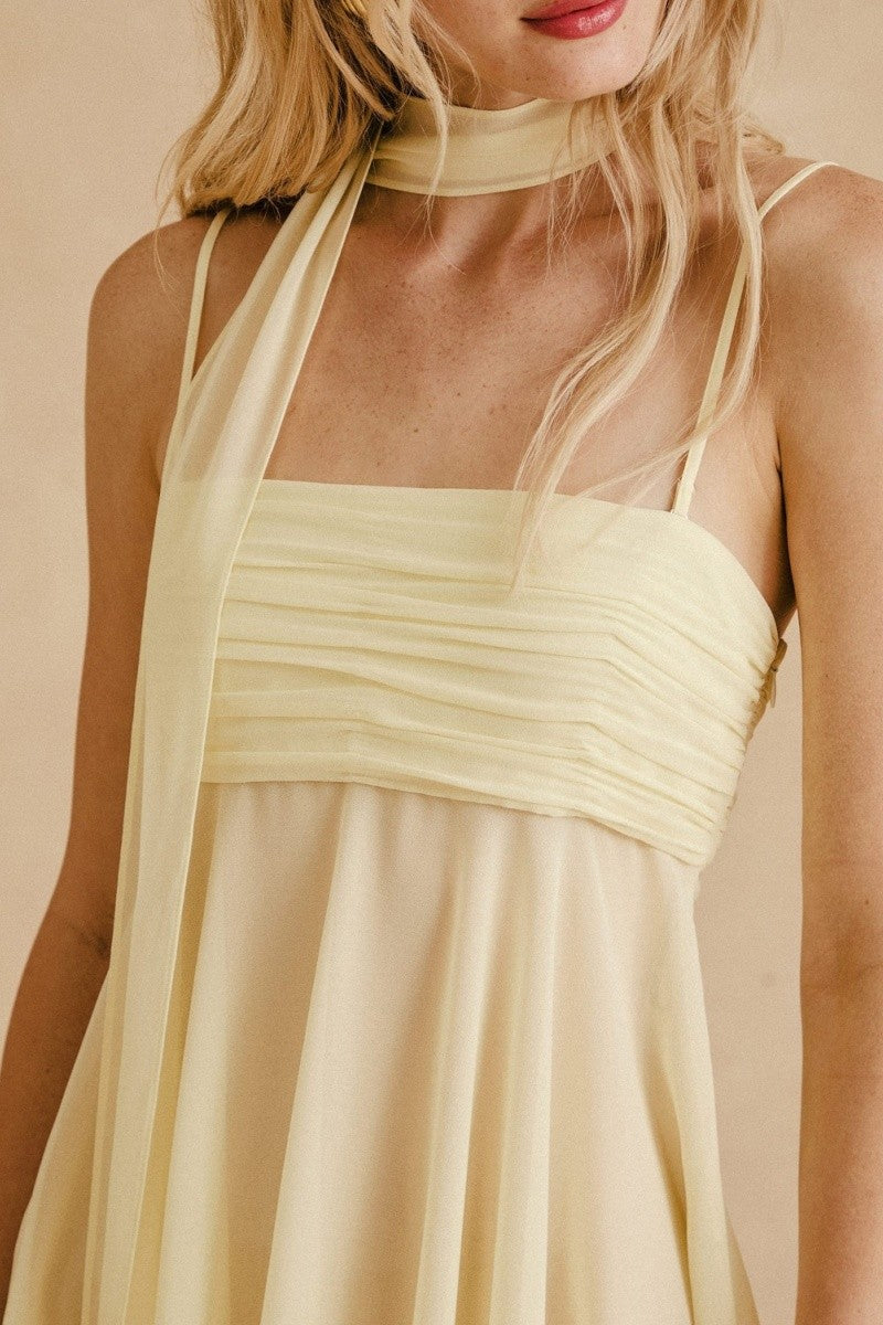 Close-up of ruched bust and spaghetti straps on yellow chiffon mini dress