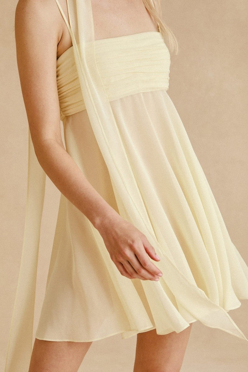 Side angle showing flowy skirt and scarf tie on yellow mini dress