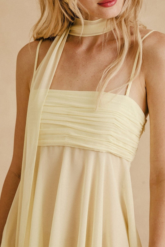 Close-up of ruched bust and spaghetti straps on yellow chiffon mini dress
