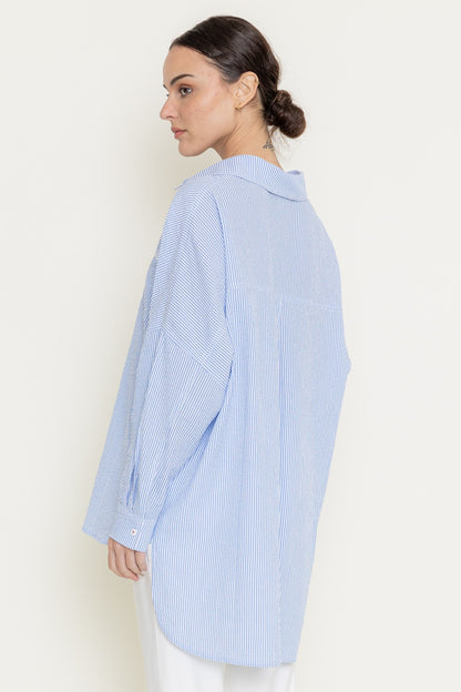Model styling oversized striped shirt with white trousers for a smart-casual look
