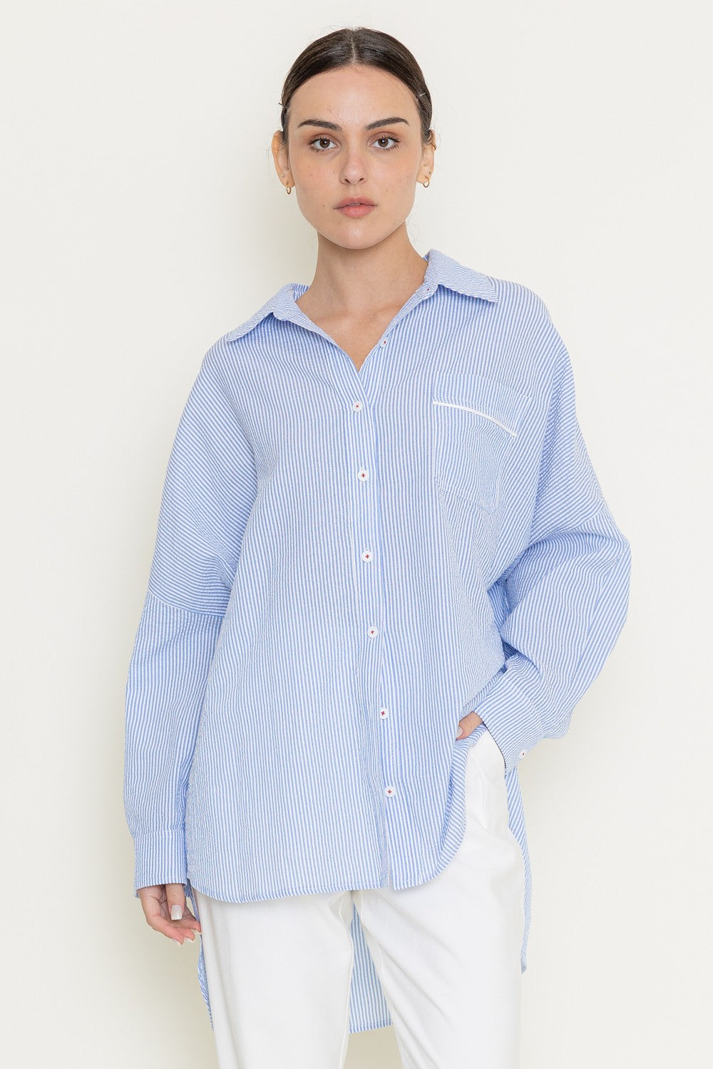 Model wearing oversized blue pinstripe button-up shirt with curved hem