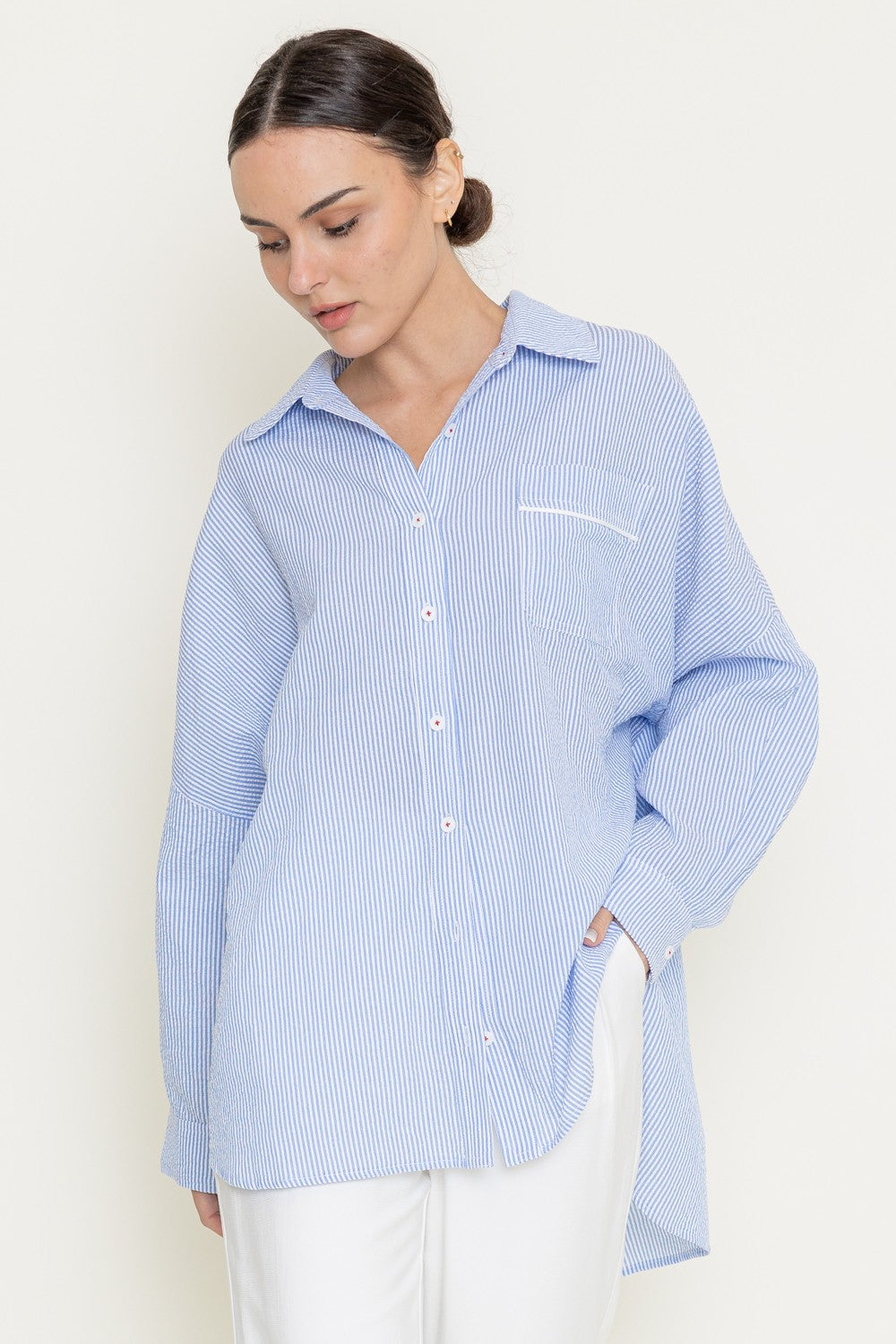 Side profile showcasing high-low hem and oversized fit of button-up shirt